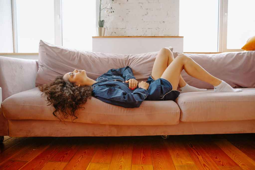 woman suffering from a stomach pain lying down on couch